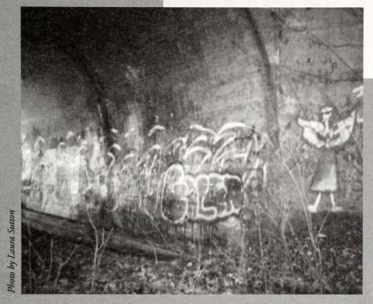 "Lydia is Here." Photograph of drawing of angel and graffiti in the underpass to the abandoned bridge near E. Main Street in Jamestown, North Carolina. The ghost "Lydia" is believed to haunt the site.  Image from the North Carolina Folklore Journal, Midwinter 2000.